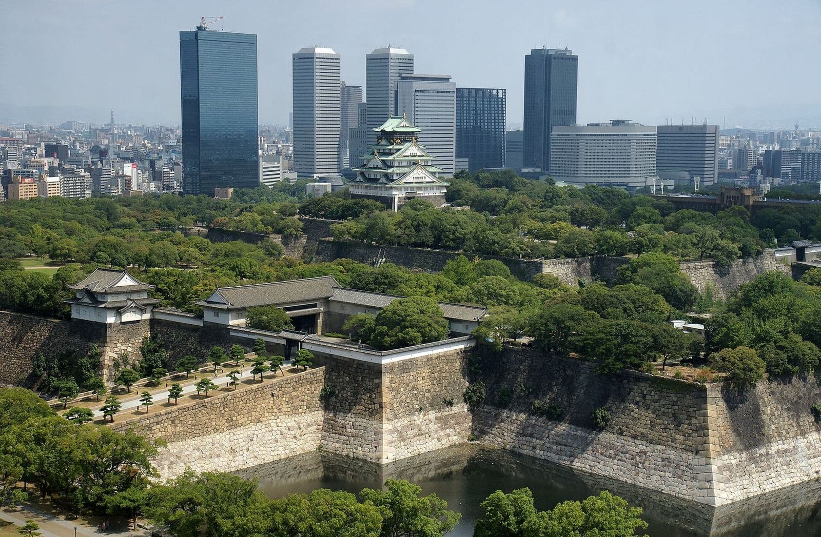 Torre del castillo de Osaka sobre sus murallas y fosos, con los rascacielos del Osaka Business Park detrás